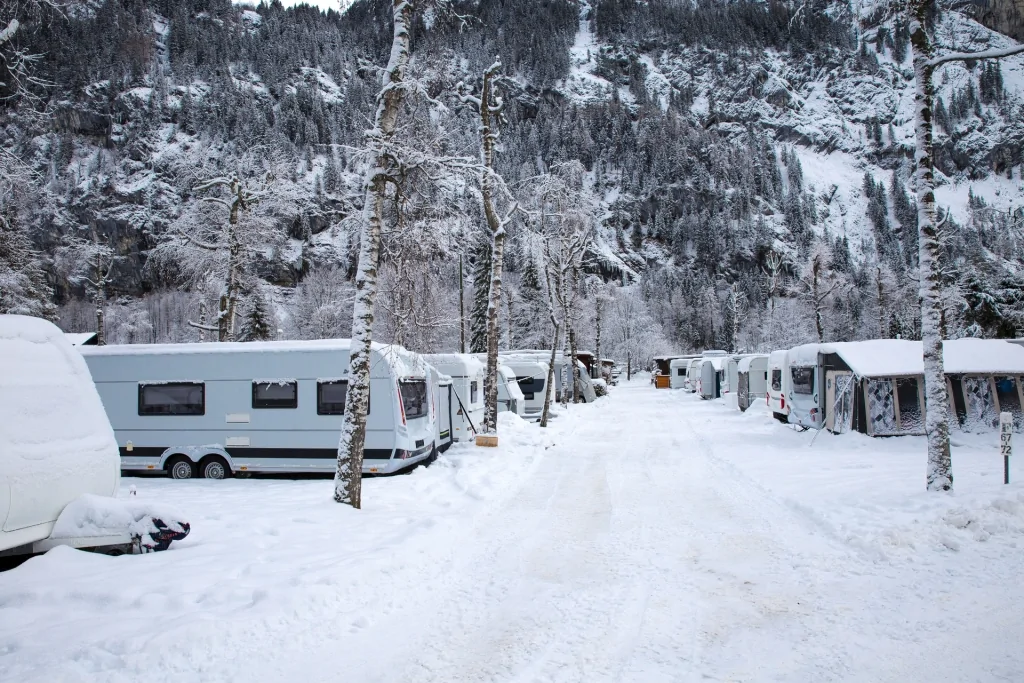 Verschneiter Campingplatz mit schneebedeckten Bäumen und Wohnmobilen